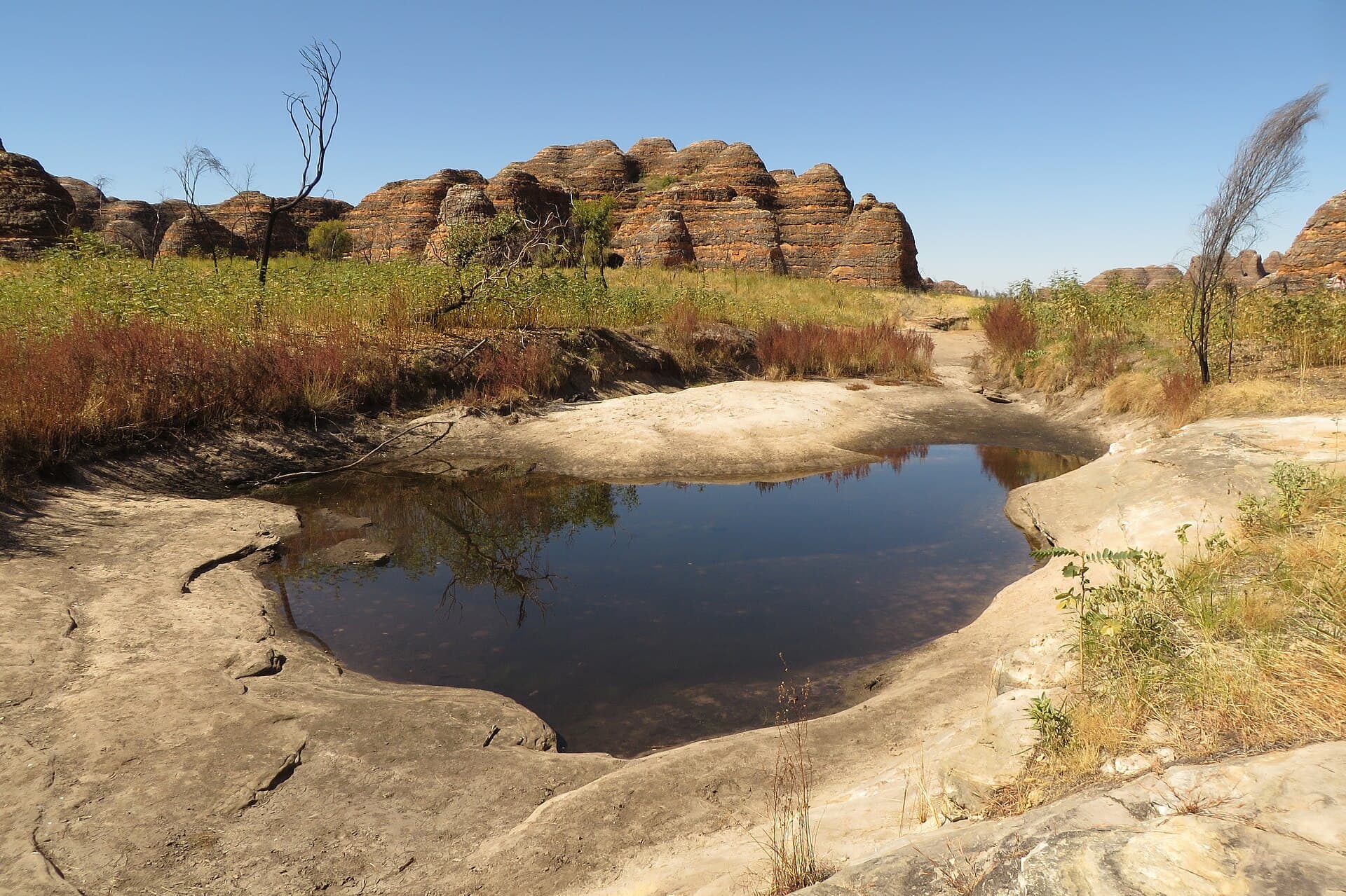 Still water reflecting banded Bungle Bungle sandstone after rain.